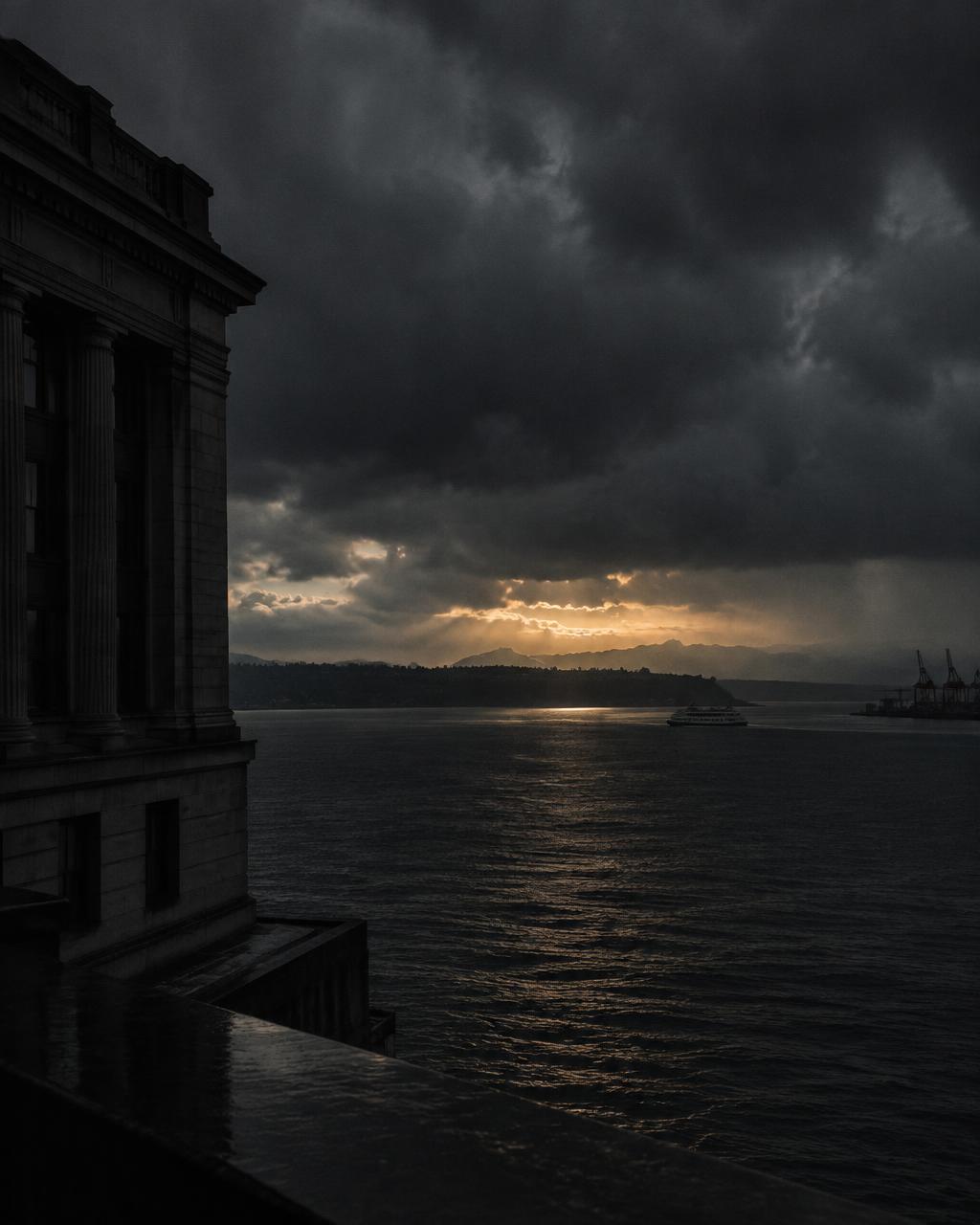 Dark storm clouds over Elliott Bay beside a stone building